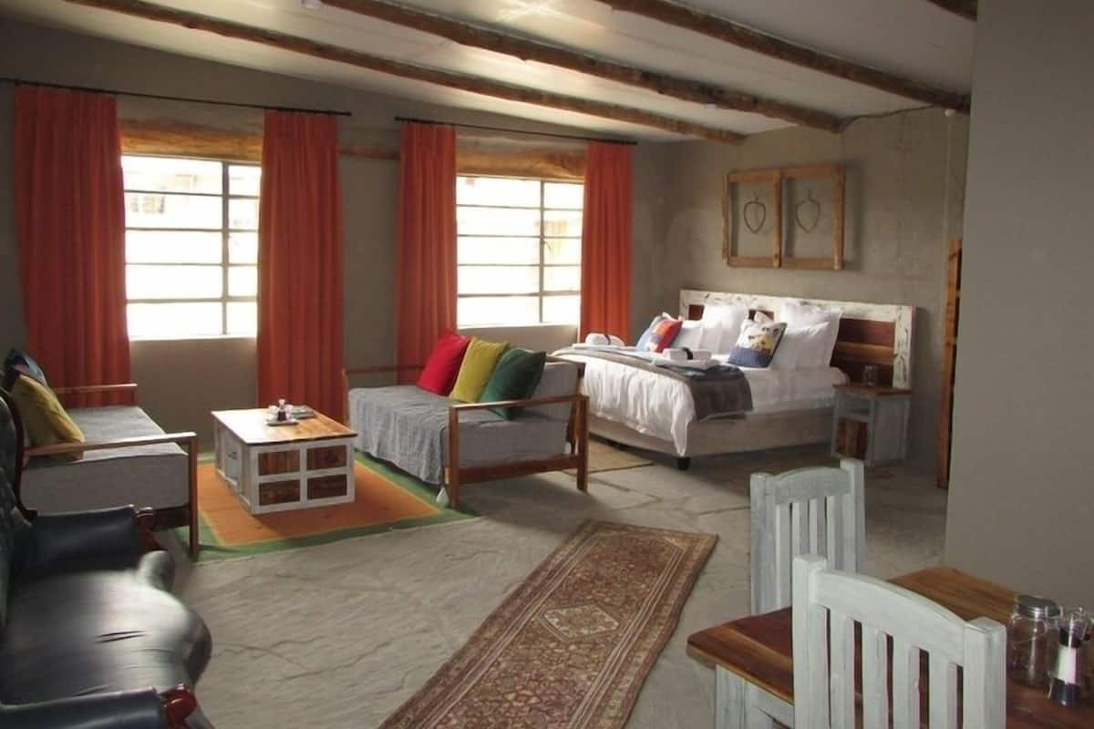 A cozy room with a bed, a sofa, a small table, and a chair.