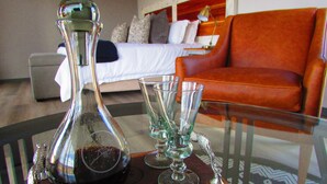 A room with a bed, a glass table with a bottle and glasses, and an orange sofa. - Rogge Cloof (Karoo Hoogland)