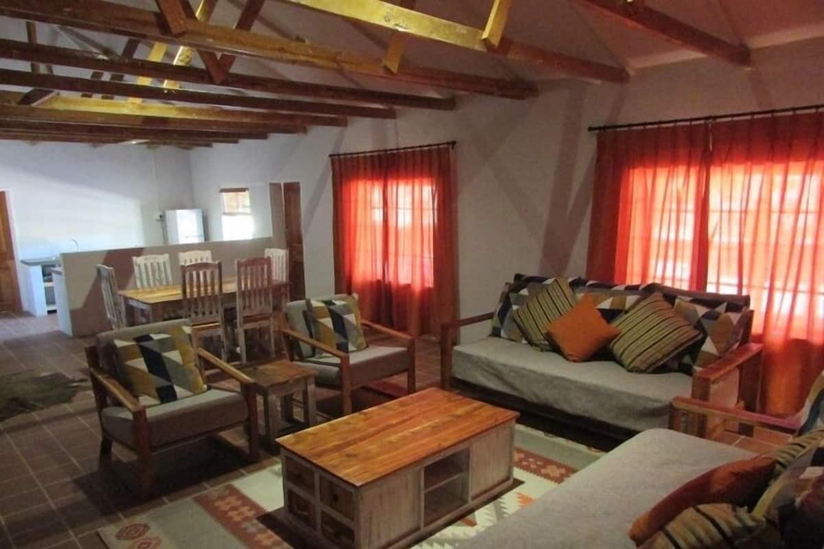 A cozy living room with a sofa, chairs, a coffee table, and a dining area with a table and chairs.