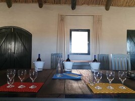 Uma mesa de jantar com copos e garrafas de vinho, uma janela com cortinas e um teto rústico.