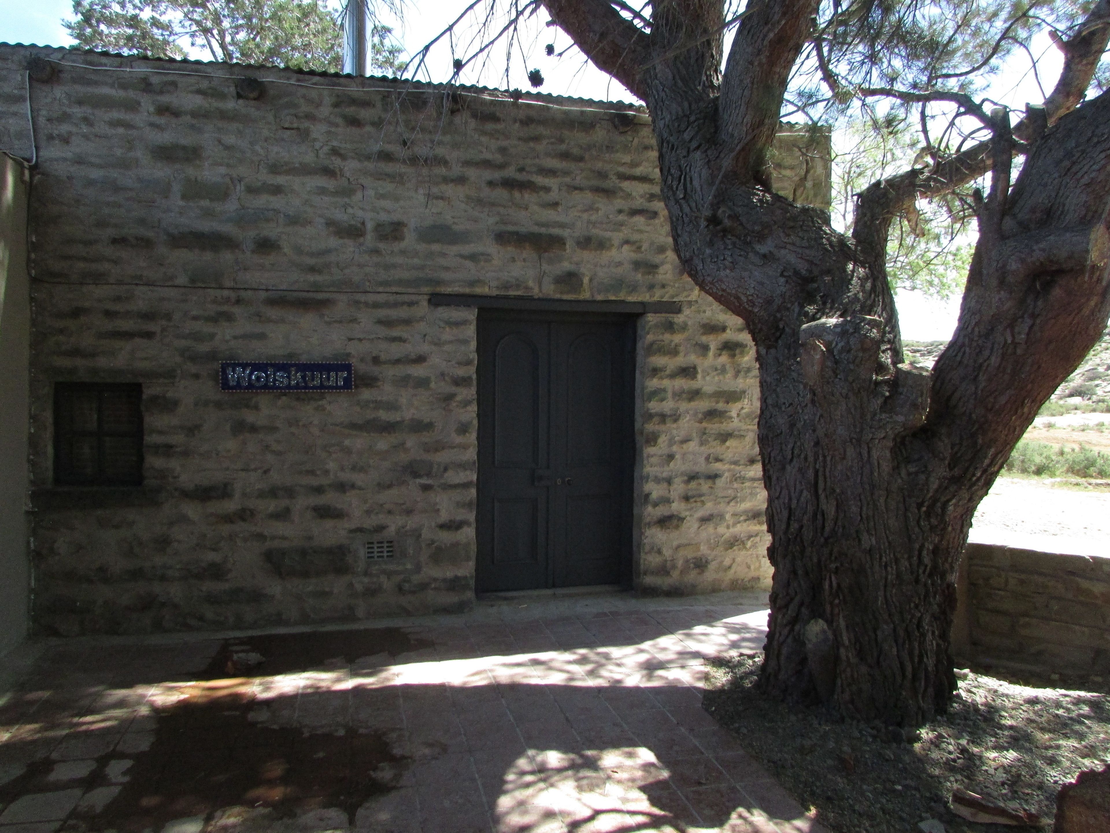 A stone building with a sign reading "Wolskuur" and a black door.
