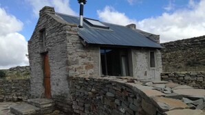 A stone cottage with a metal roof, a chimney, and a wooden door. - Rogge Cloof (Karoo Hoogland)