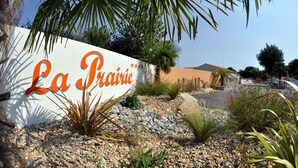 Un letrero de 'La Prairie' con un jardín paisajista que incluye rocas, cactus y palmeras.