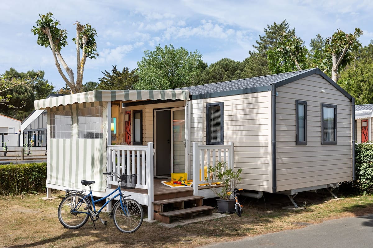 A mobile home with a porch, a bicycle, and a small garden.