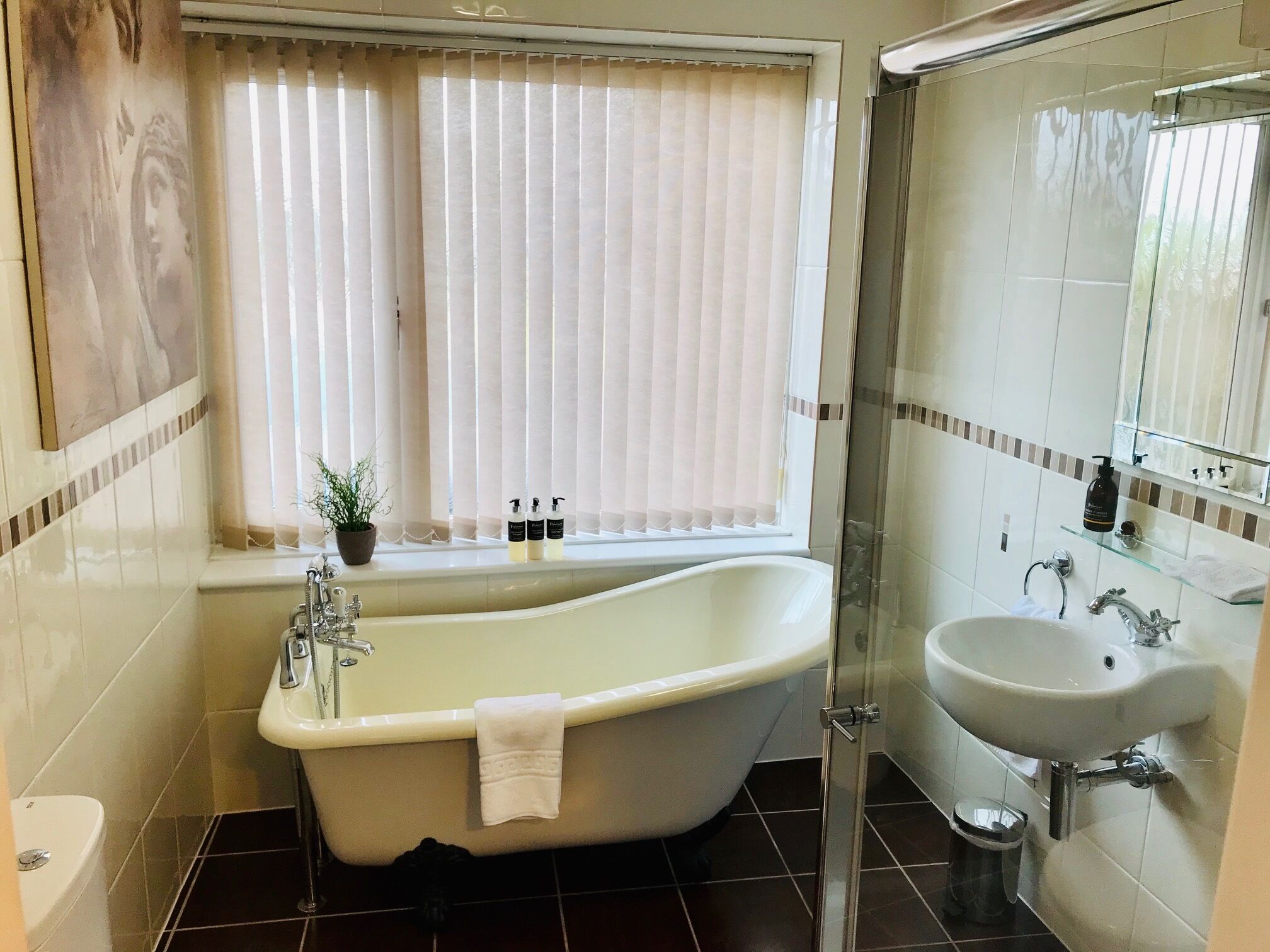 Ein Badezimmer mit freistehender Badewanne, einer begehbaren Duschkabine und einem Waschbecken.