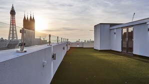 A rooftop terrace with a view of the Eiffel Tower and a modern building. - Winter Gardens Service Apartments 2 (Blackpool)