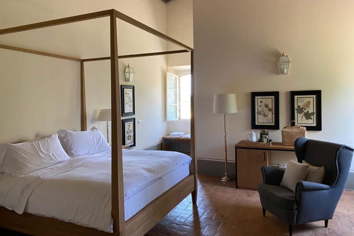 Een hemelbed met nachtkastje, een bureau met stoel en lijstwerken aan de muur.