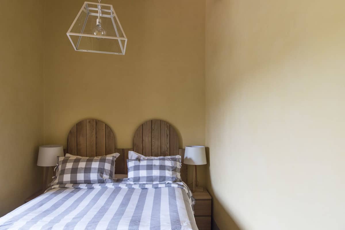 Een bed met een gestreept laken, twee houten hoofdborden en twee bedlampen.
