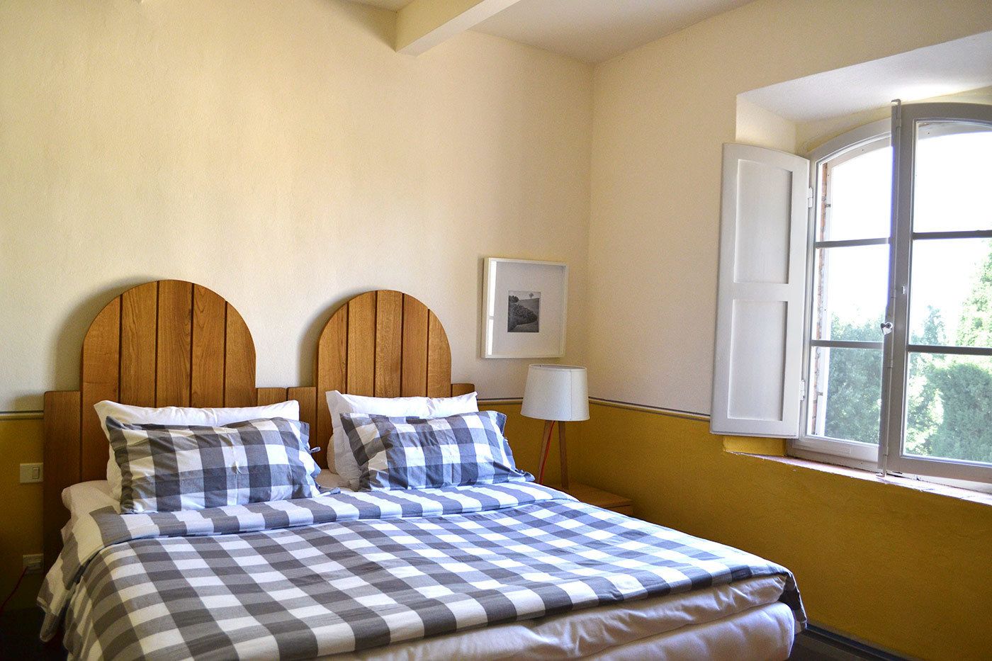 A bedroom with a bed, a window, and a wall-mounted picture.