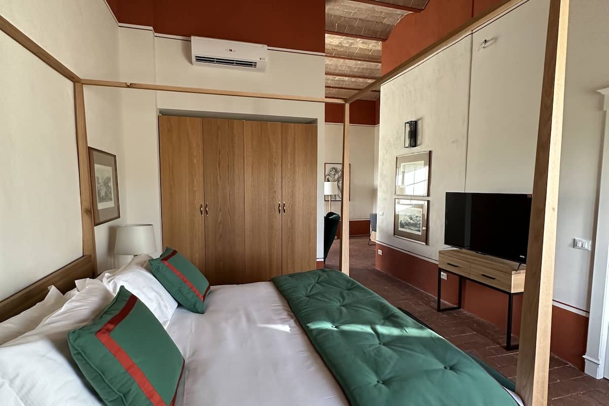 Een hotelkamer met een houten bed, een televisie en een kledingkast.