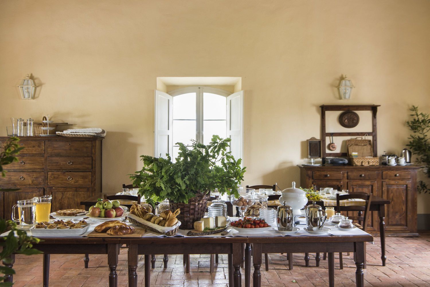 Uma área de refeições com mesa posta para o café da manhã, incluindo pão, frutas e bebidas.
