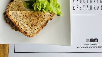 A plate with grilled vegetables, a slice of bread, and a small bowl of sauce.
