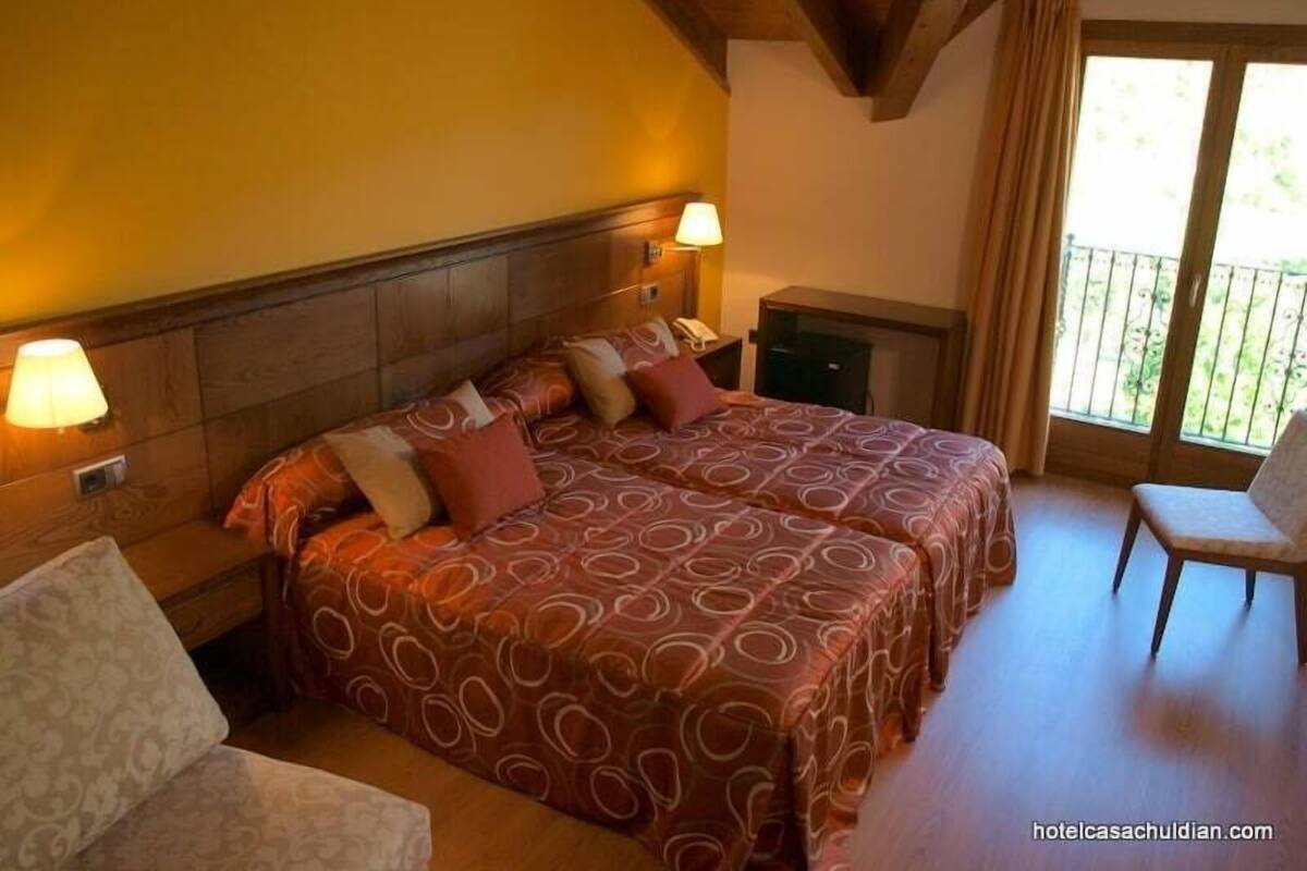 A hotel room with two beds, a small desk, and a chair.