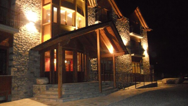 Un edificio de piedra con un porche de madera y una escalera que lleva a la entrada.