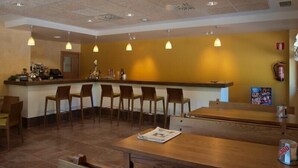 Un restaurante con mostrador, taburetes de bar y una mesa de madera.