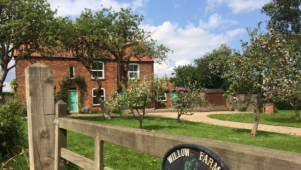 A wooden fence with a sign that reads "WILLOW FARM COTTAGE".
