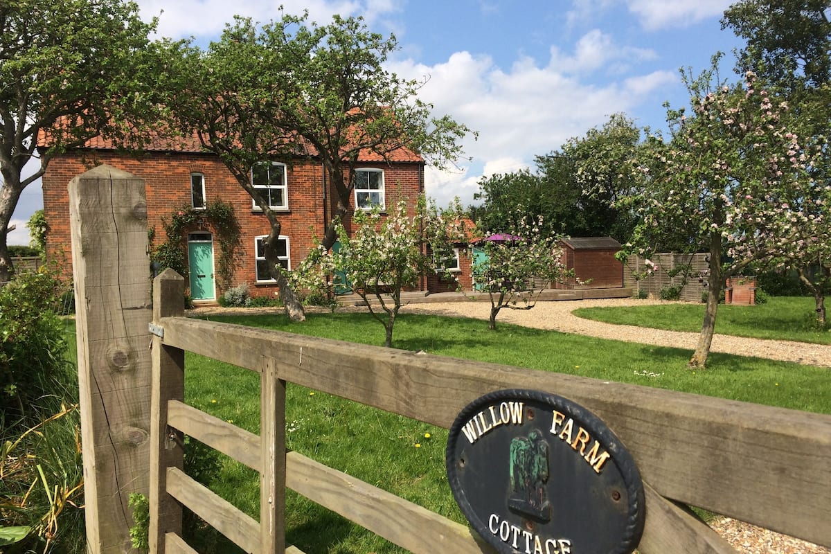 Un recinto di legno con un cartello che riporta la scritta 'WILLOW FARM COTTAGE'.