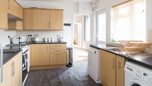 A modern kitchen with wooden cabinets, a dishwasher, and a washing machine.