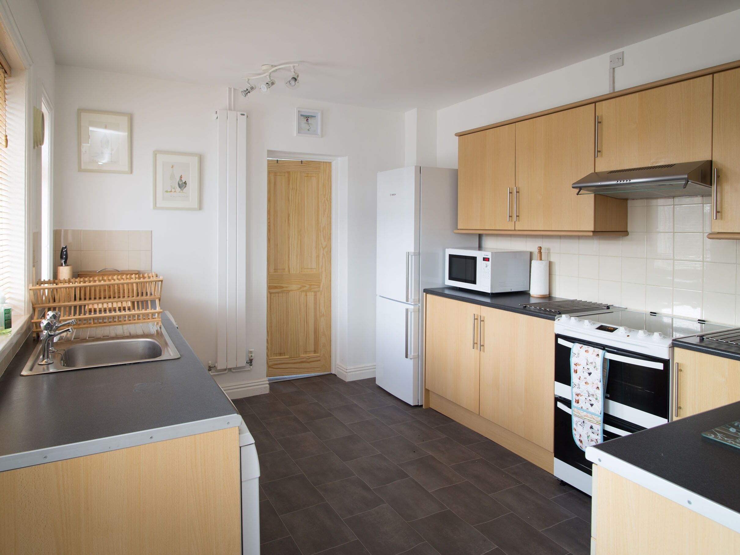 A modern kitchen with wooden cabinets, a stainless steel sink, a microwave, and a stove.