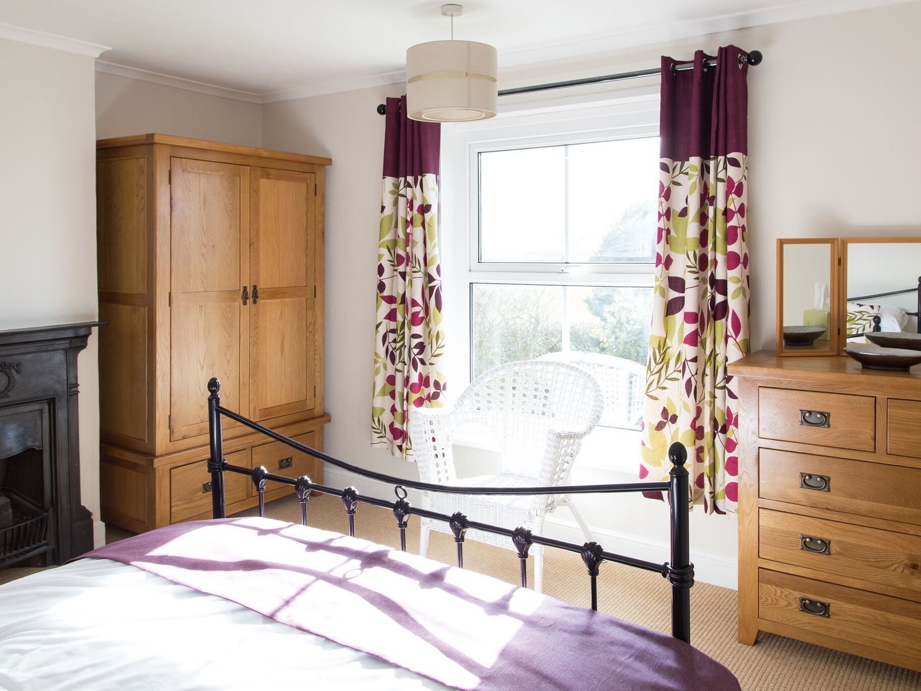 A bedroom with a bed, wooden wardrobe, and a window with curtains.