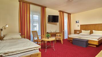 A hotel room with two beds, a desk, a TV, and a small table with a chair.