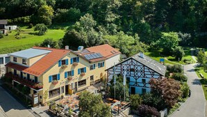 Un bâtiment européen traditionnel, avec un toit recouvert de tuiles rouges, un balcon orné de fleurs et une enseigne indiquant la présence d’un restaurant.