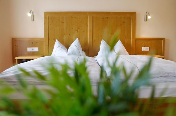 A bedroom with a wooden headboard, a bed with white bedding, two bedside tables, and wall-mounted lights. - Hotel Zum Blauen Hecht (Kipfenberg)