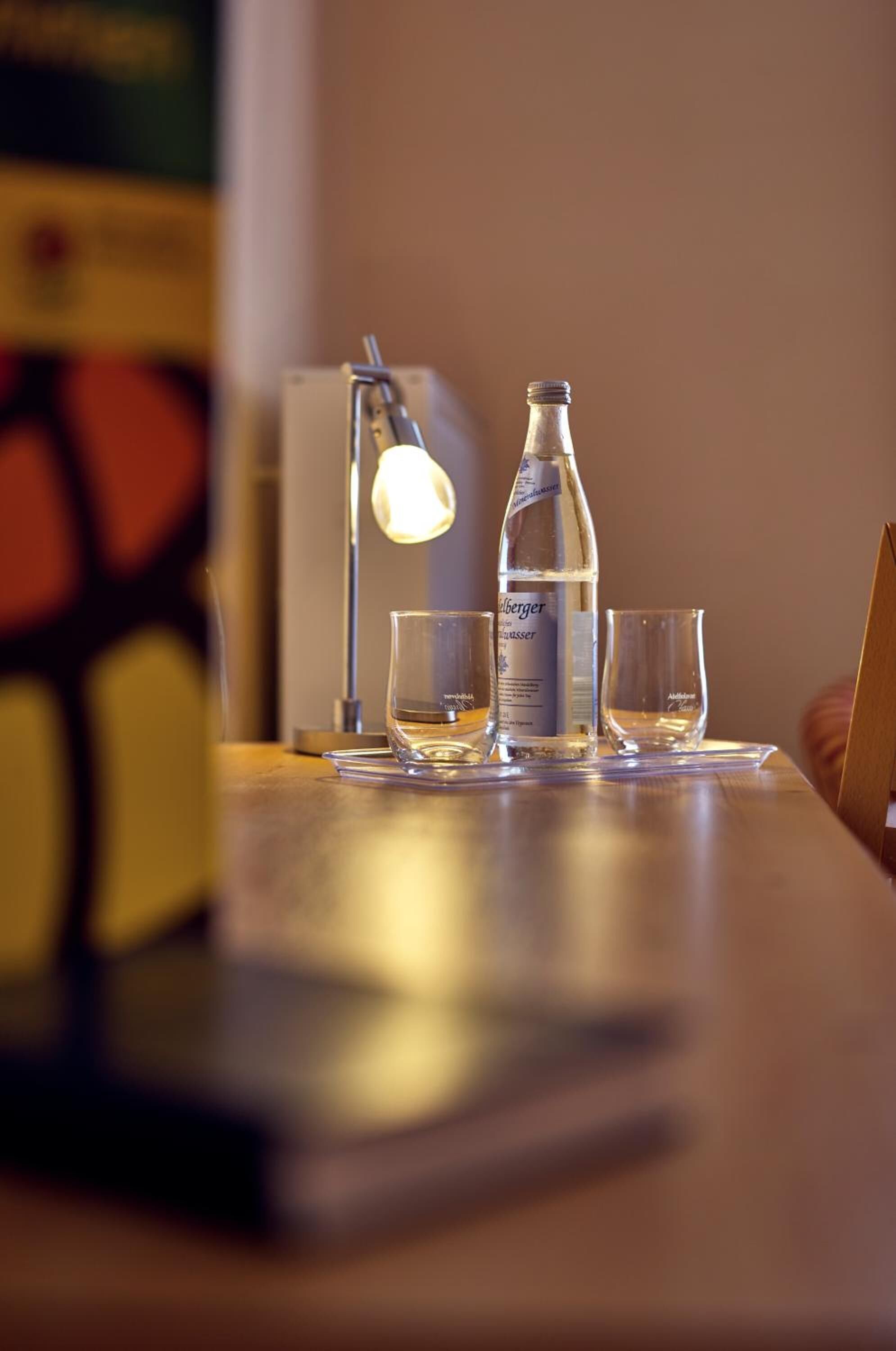 Un tavolo con una bottiglia d'acqua, due bicchieri e una lampada.