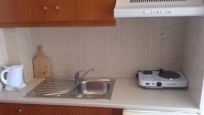 A compact kitchen with a sink, a stove, and a dishwasher. - Studios Stella (Agios Vasileios)