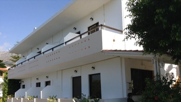 A two-story building with a balcony, outdoor seating, and potted plants. - Studios Stella (Agios Vasileios)