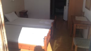 A small, well-lit room with a single bed, a wooden desk, and a chair. - Studios Stella (Agios Vasileios)