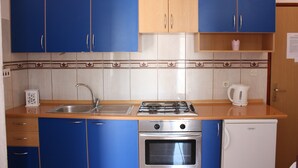Eine Küche mit blauen Schränken, einer Edelstahl-Spüle, einem Gasherd, einem Backofen und einem weißen Kühlschrank.