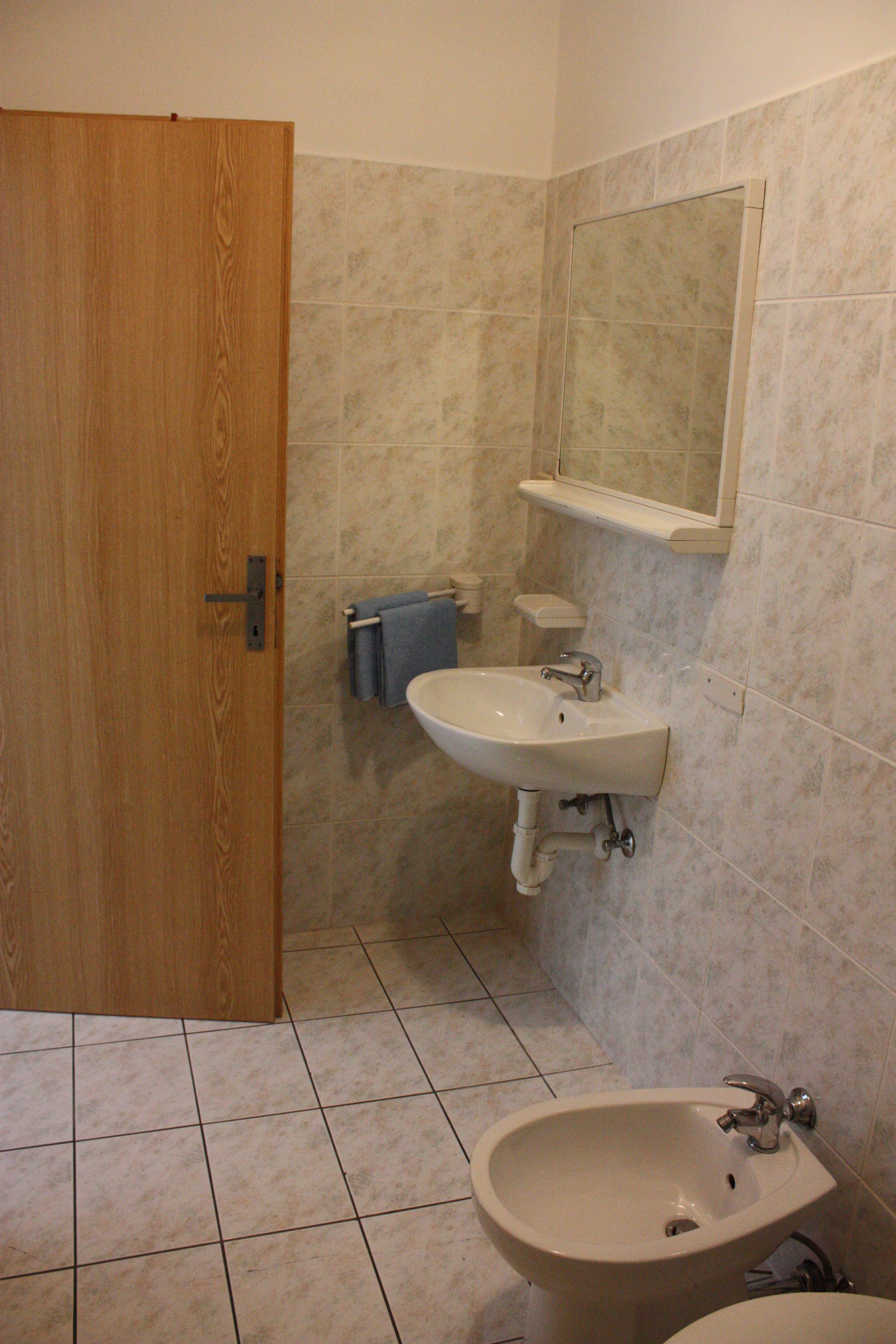 Un baño con puerta de madera, un lavabo, un bidé y un espejo.