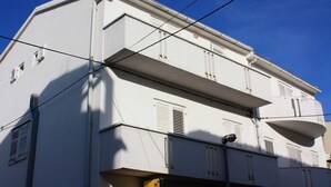 Ein weißes, mehrgeschossiges Gebäude mit Balkonen und einer gelben Beschilderung.