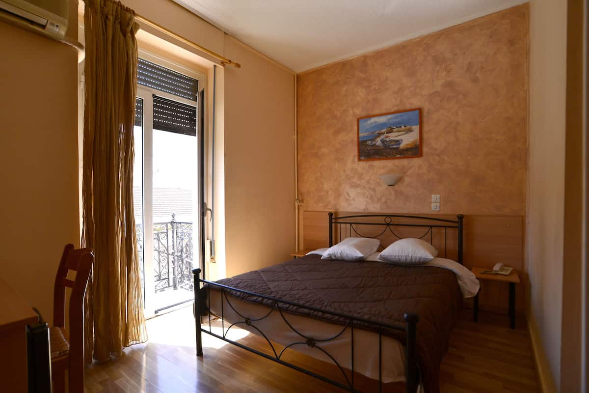 A bedroom with a bed, a chair, a nightstand, and a painting on the wall.