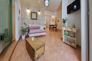 Un salon chaleureux avec un canapé, une table basse en bois et un téléviseur fixé au mur.