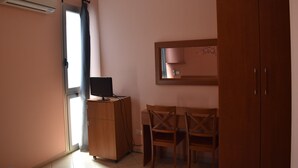 Una habitación con un escritorio de madera, una silla, un armario y un espejo en la pared.