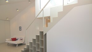 A modern interior with a white staircase, a white sofa with red and blue pillows, and a small framed picture on the wall. - Boutique Apartments Palcic Palace (Pag)