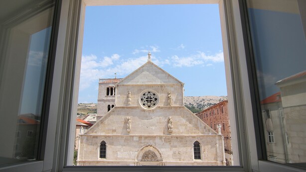 A church with a prominent circular window and two statues on the facade. - Boutique Apartments Palcic Palace (Pag)