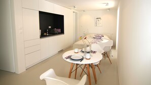A compact kitchen with white cabinetry, a black countertop, and a dining area with a white table and chairs. - Boutique Apartments Palcic Palace (Pag)