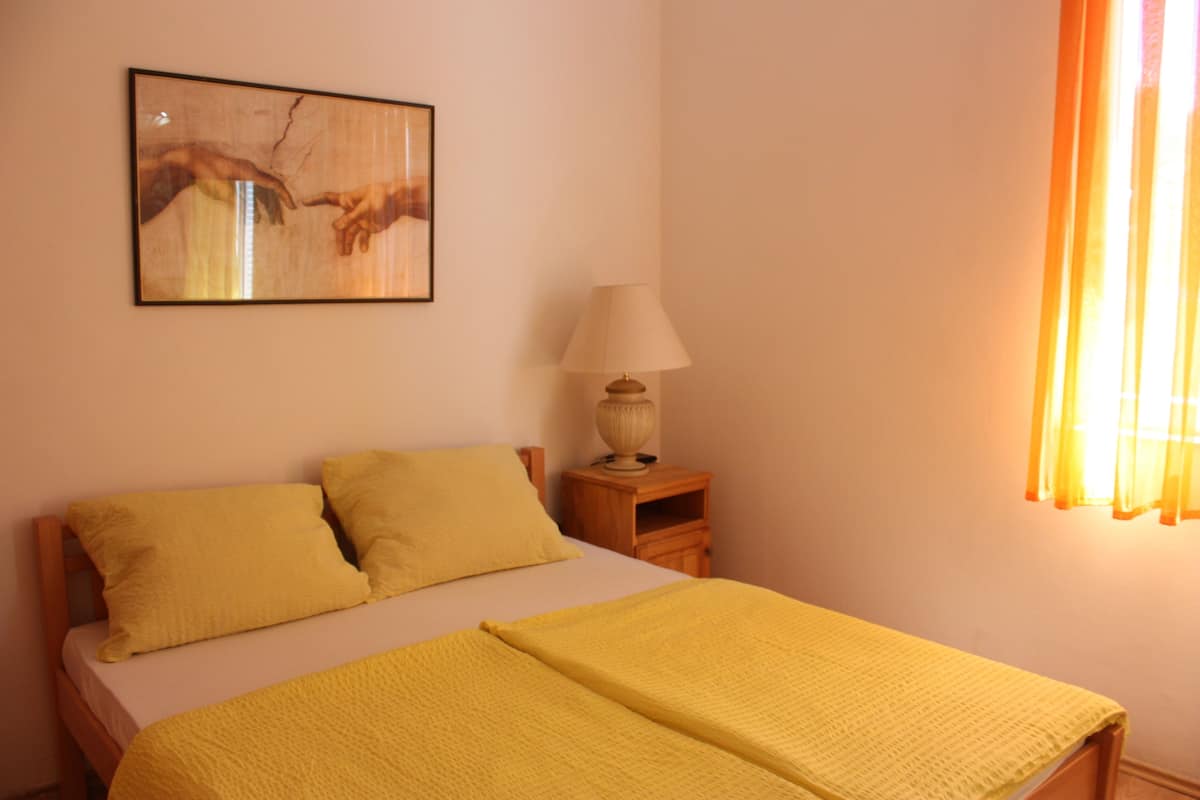 A room with a bed, a nightstand with a lamp, and a painting on the wall.