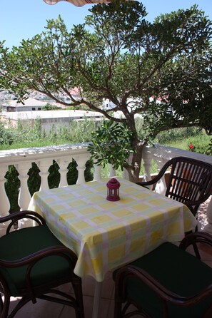Una mesa al aire libre con mantel a cuadros, dos sillas y un farol.