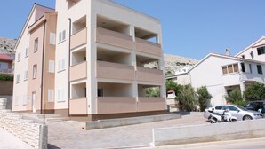 Um edifício residencial com várias andares, varandas e um acesso pavimentado.