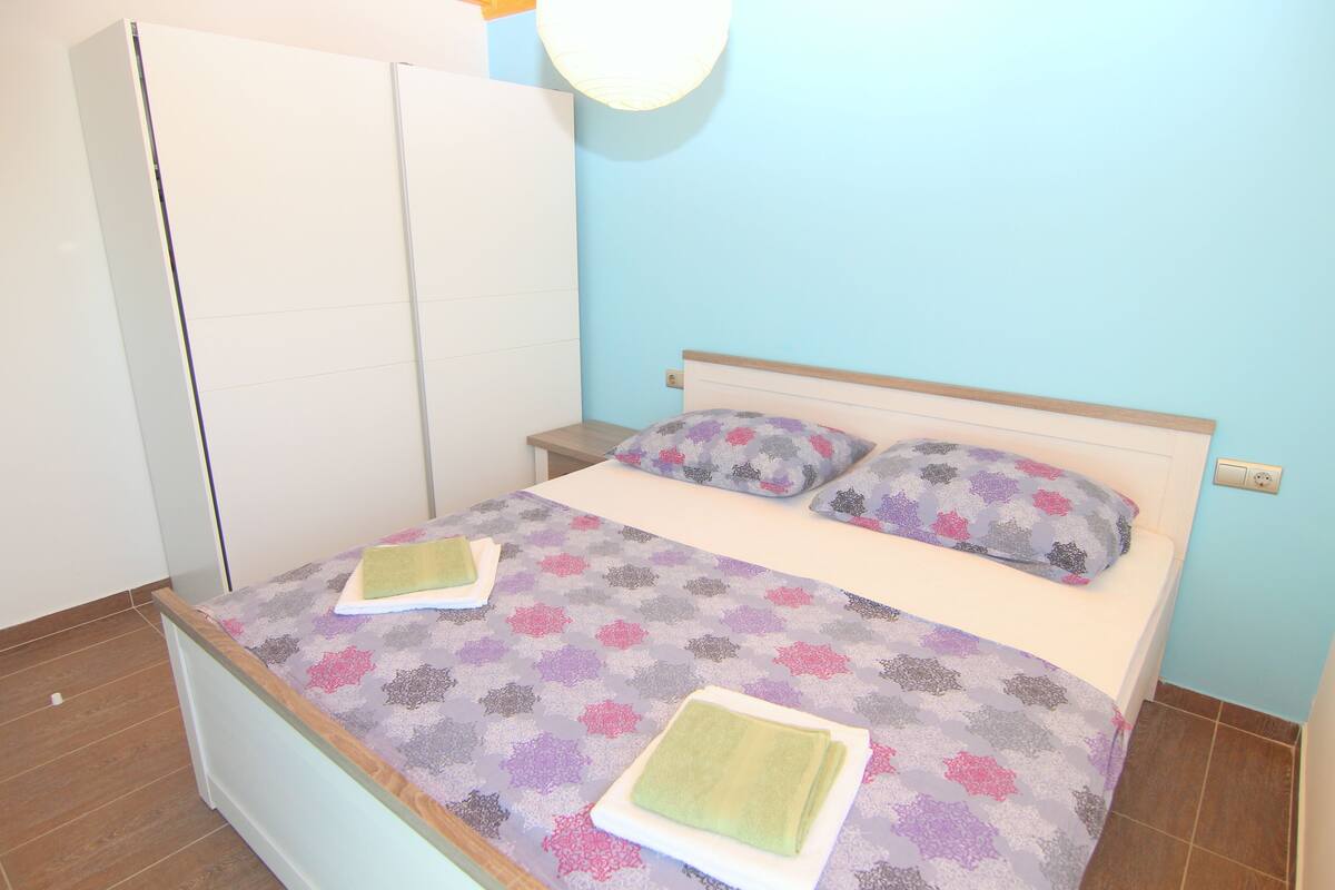 A bedroom with a bed, a wardrobe, and a nightstand.