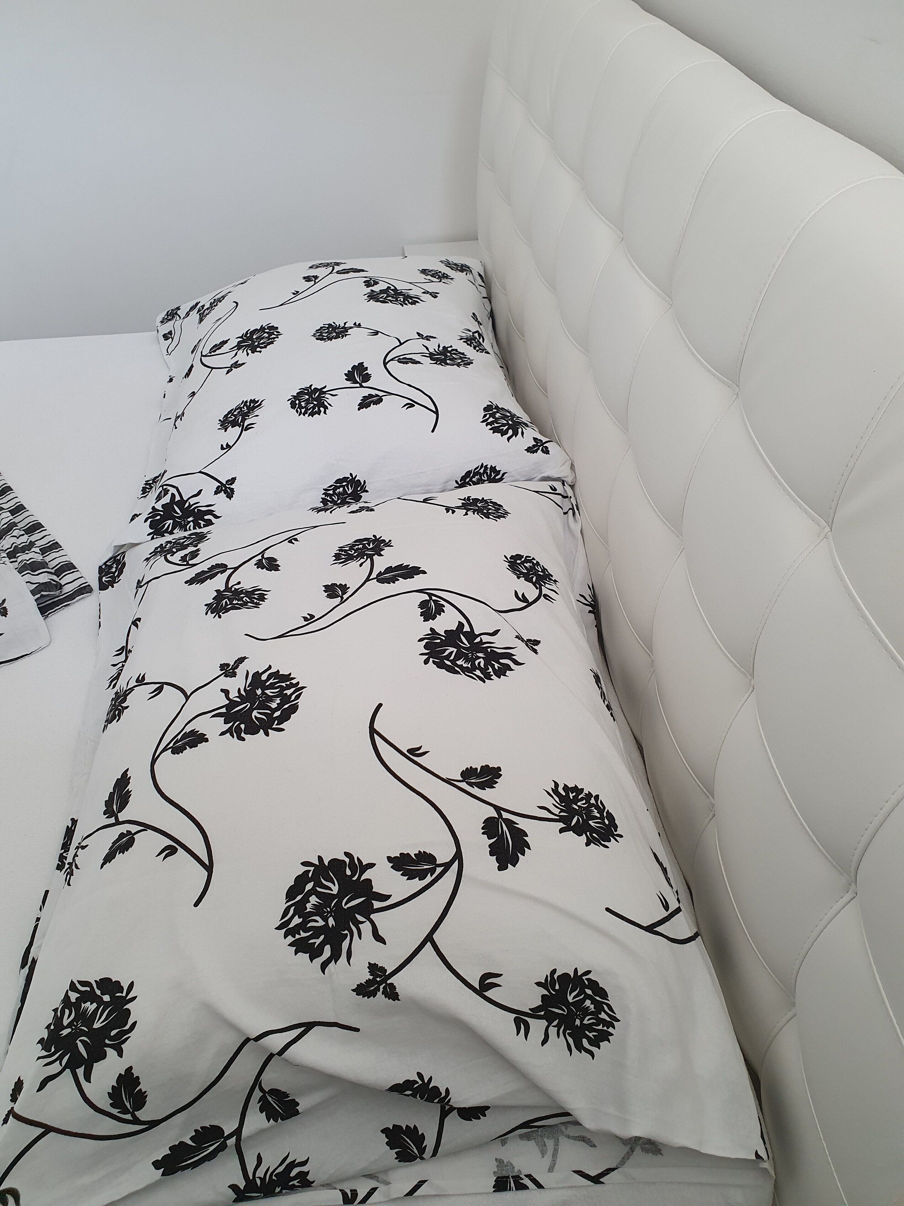 Un lit avec une couvre-lit à motifs floraux et une tête de lit capitonnée.
