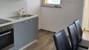 A modern kitchen with grey cabinets, a stainless steel sink, and a window with a view of the outdoors. - Apartments Ljubic (Pag)