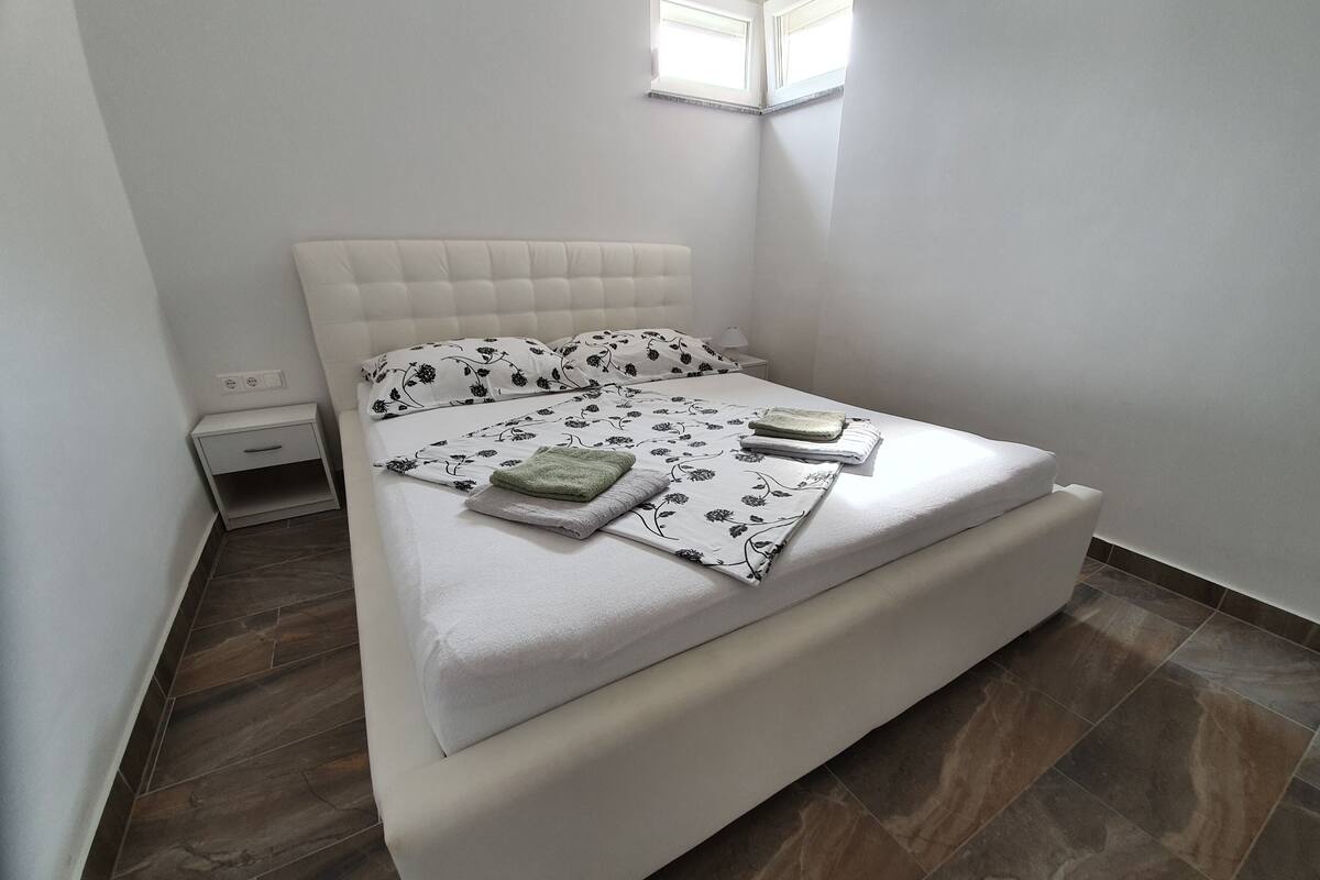 A neatly made bed with floral bedding, a bedside table, and a nightstand.
