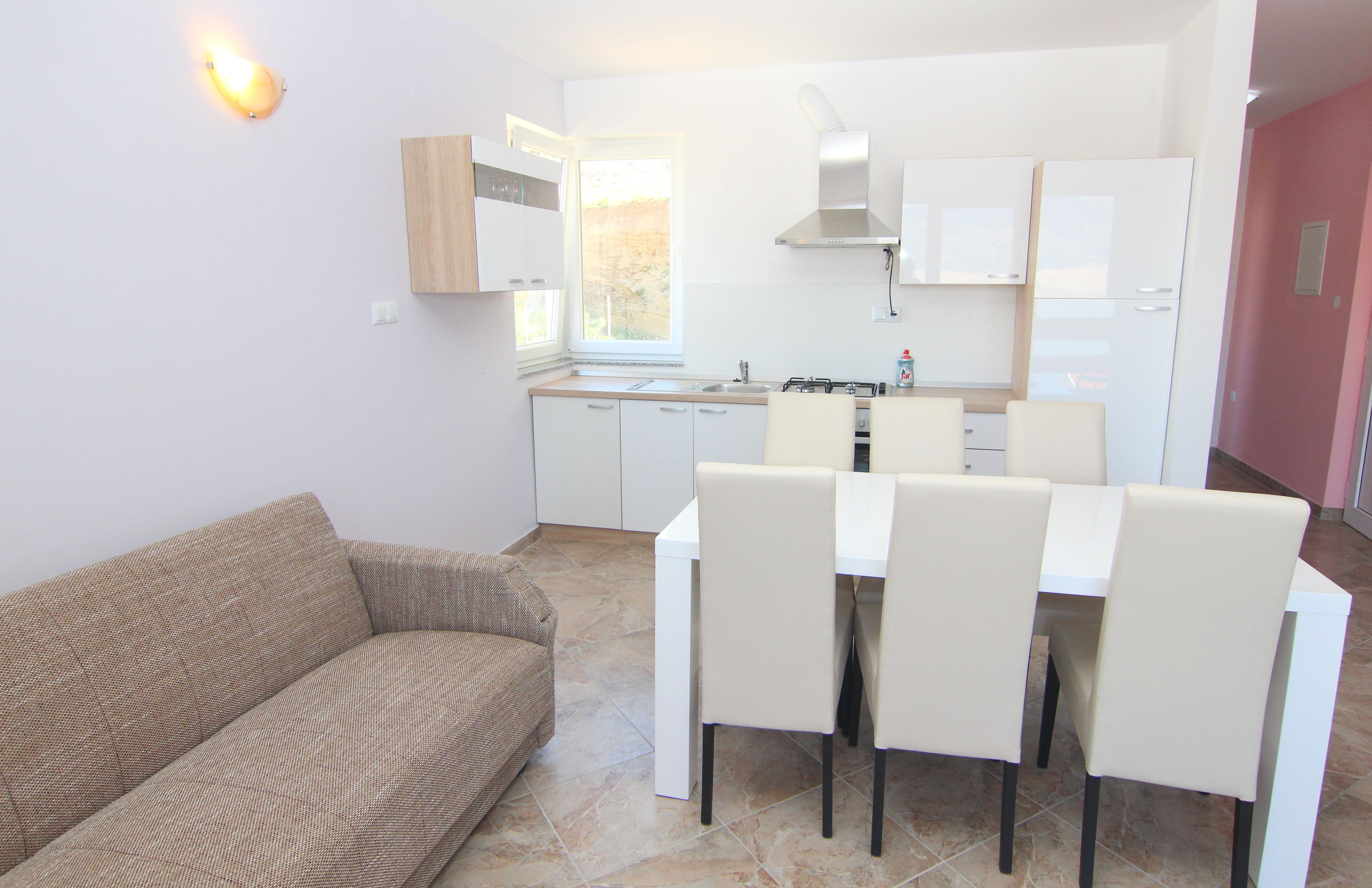 A compact living space with a kitchenette, a dining area with a table and chairs, and a sofa.