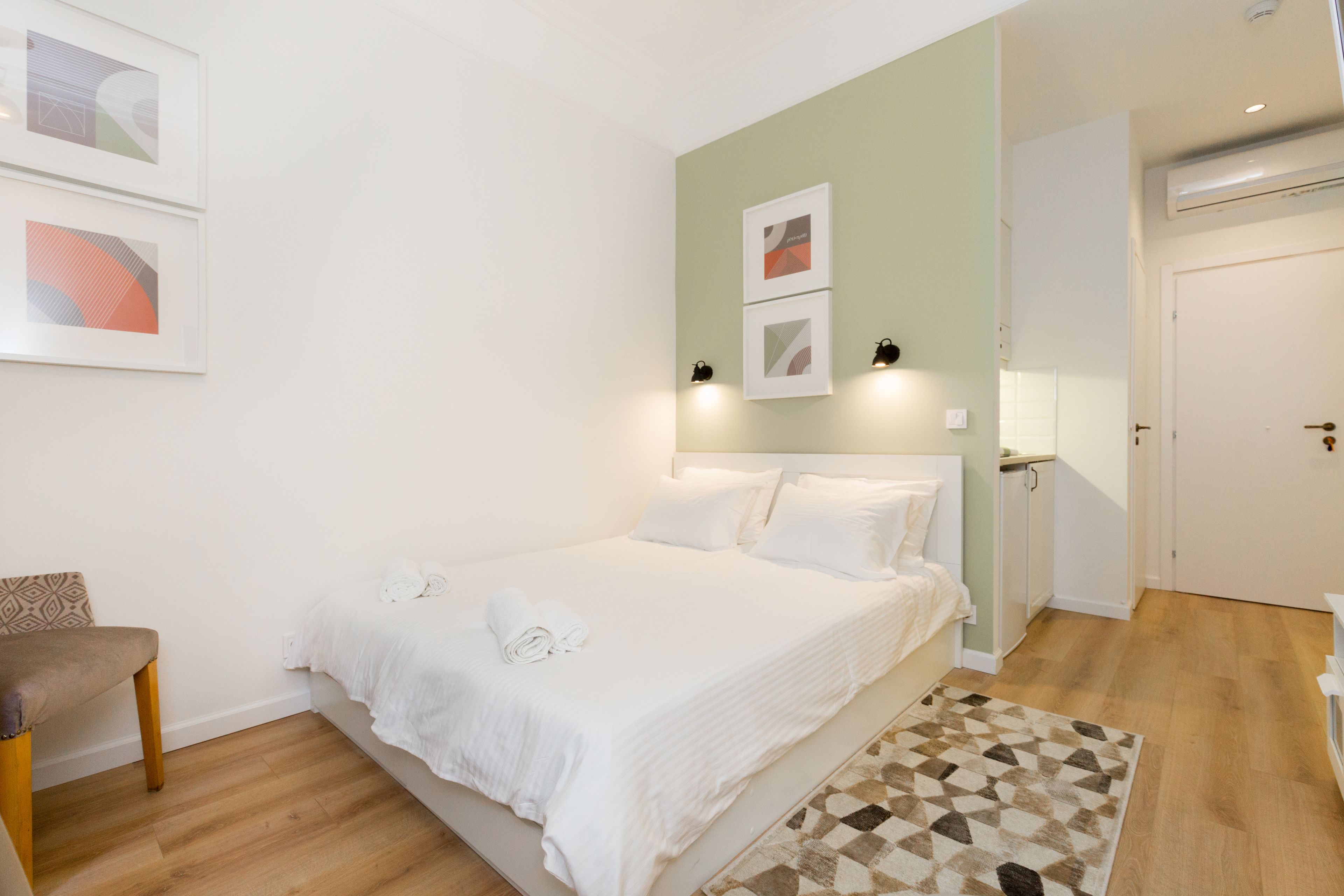 A neatly arranged bedroom with a bed, a chair, and a door.