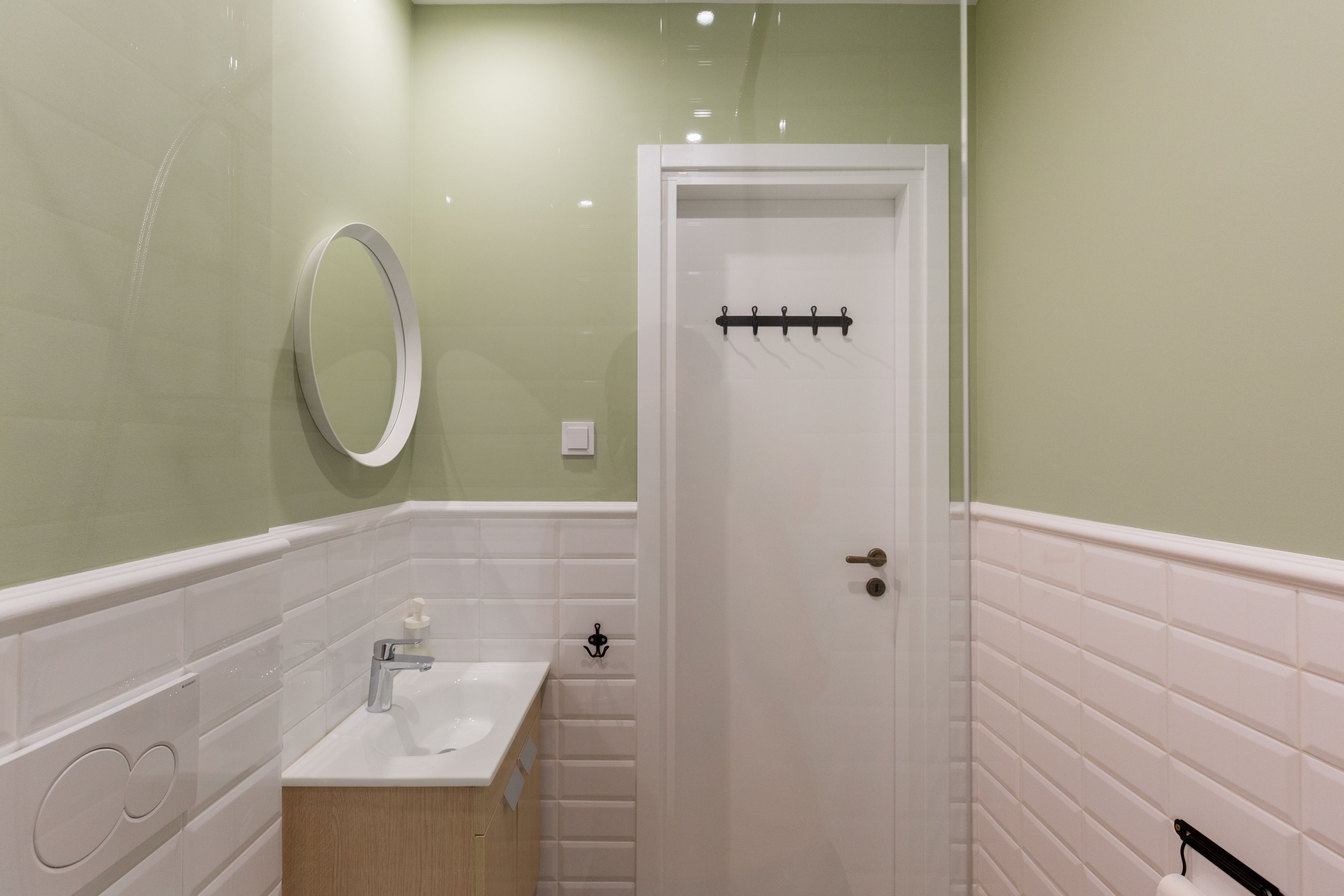 A bathroom with a white sink, mirror, and door.
